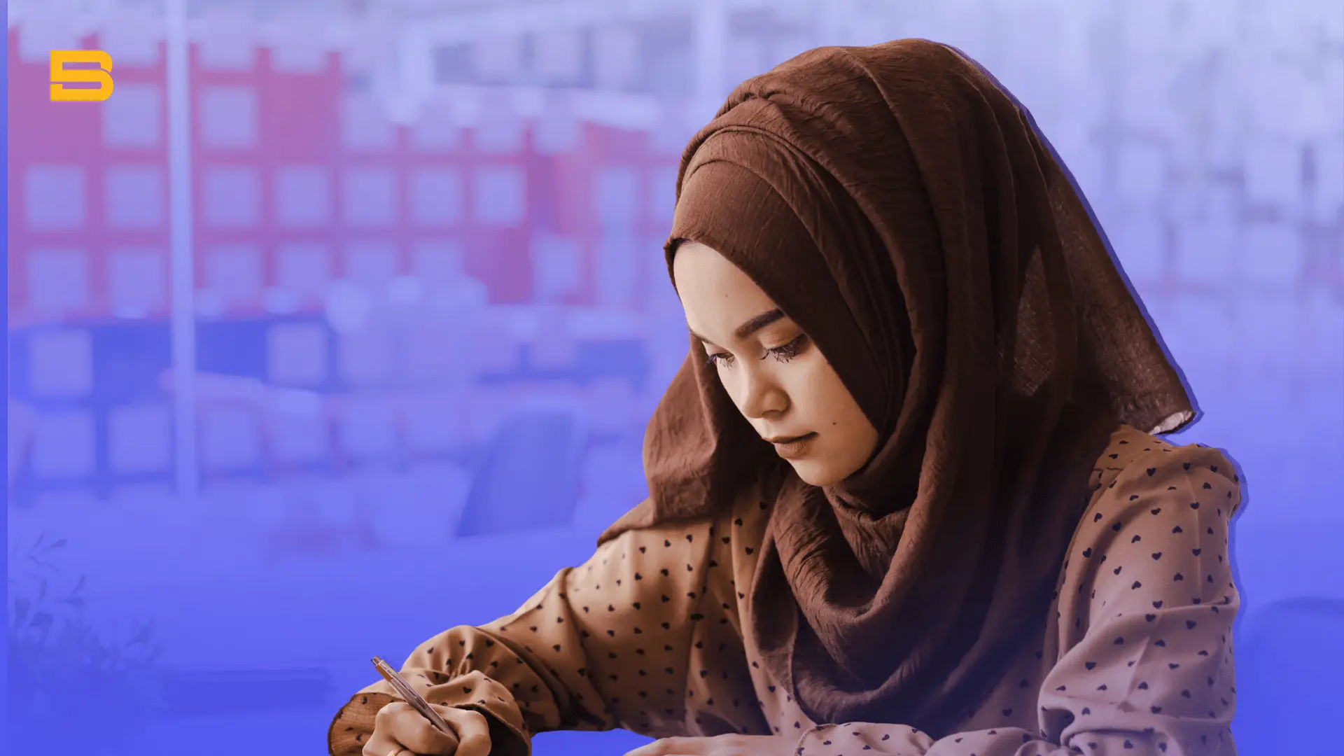 Muslim woman in a hijab writing notes at a desk while researching.